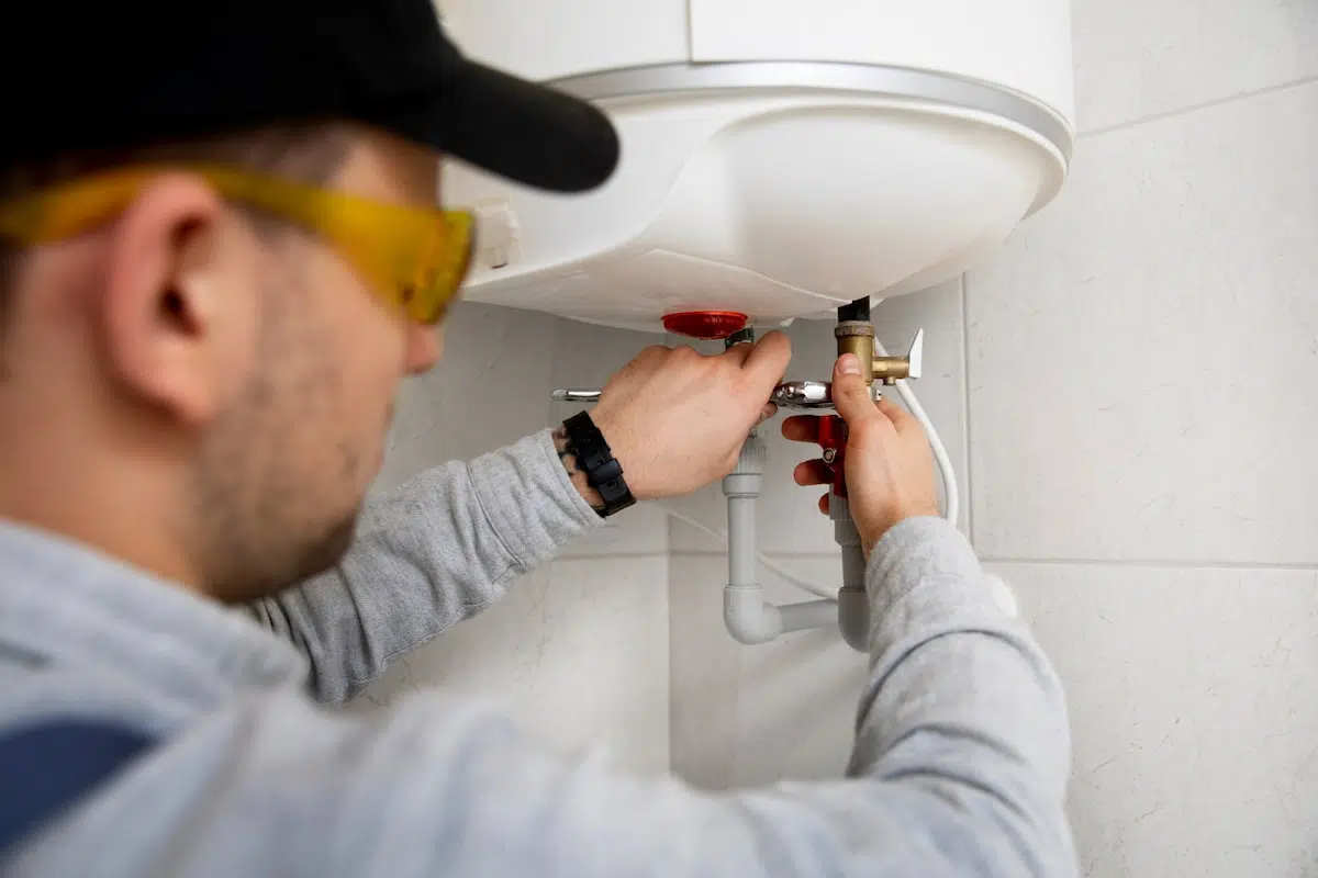 montaj boiler cu serpentina - un instalator lucreaza la montarea unui boiler electric pe un perete
