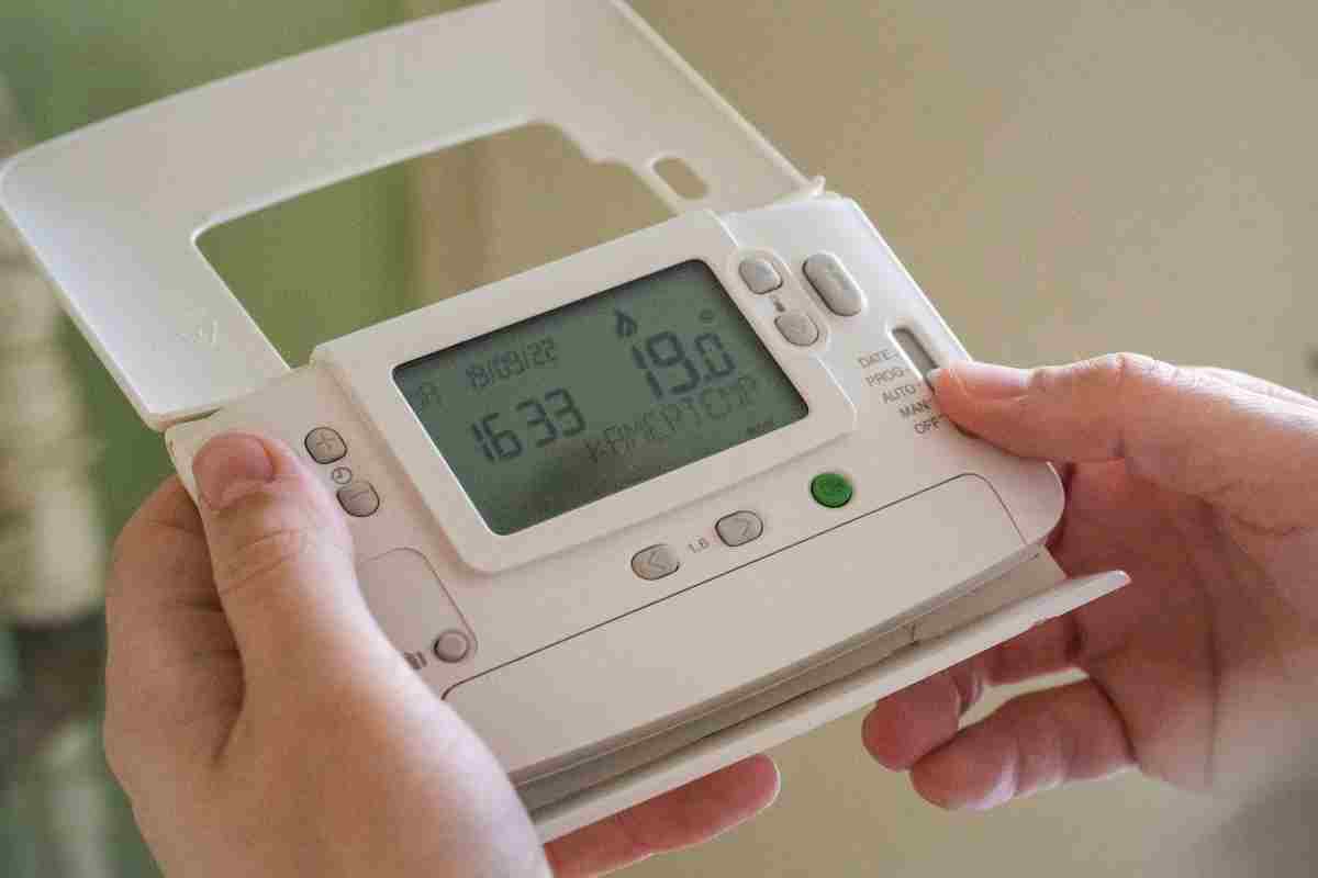 Termostat cu fir vs termostat fara fir - avantaje si dezavantaje_Persoana setand temperatura la termostatul wireless, fara fir