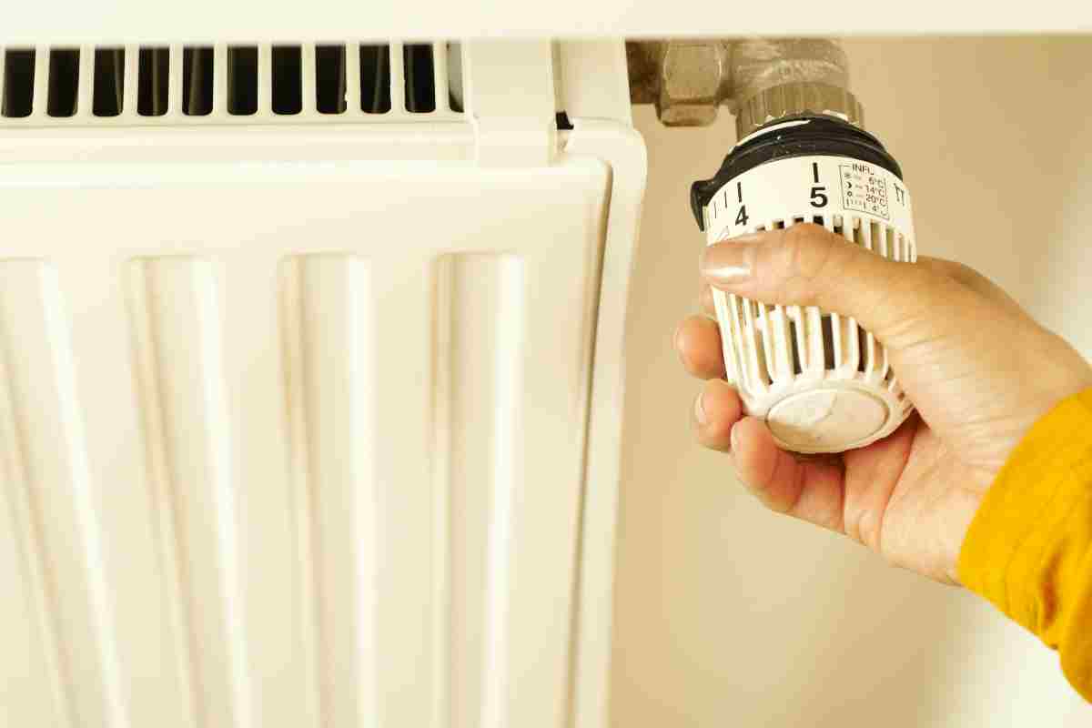 Cum alegi tipul potrivit de termostat pentru centrala ta_Persoana regland temperatura de la calorifer, camera