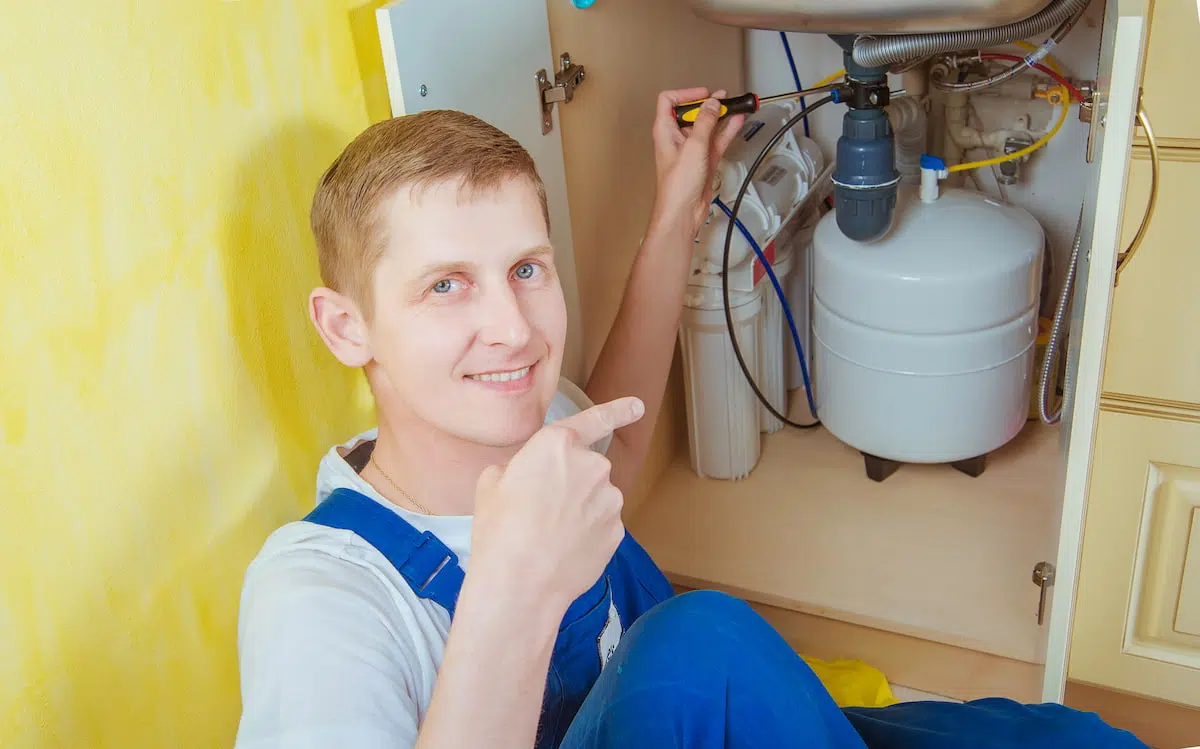 3. Montaj filtre apa - un instalator lucrand la montajul unui filtru de apa sub o chiuveta de bucatarie