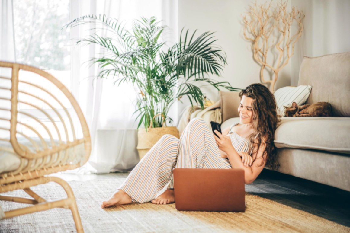 Gresia pentru încălzirea în pardoseală (fotografie de cover cu o femeie fericita care isi petrece timpul intr-un living minimalist cu accente vegetale) - romstal.ro
