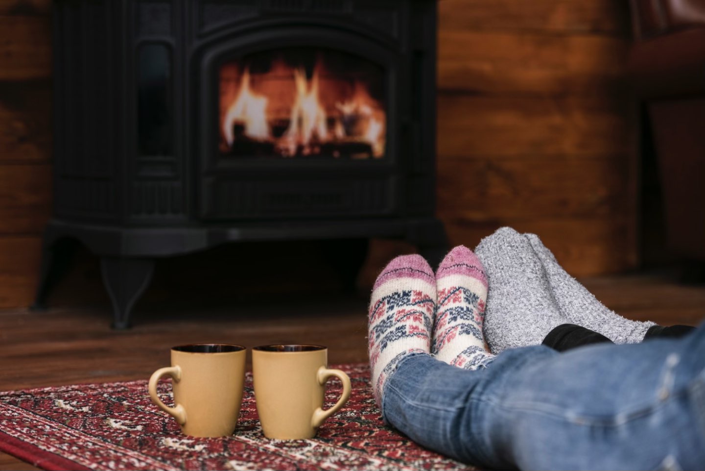Sobe pentru locuinte (imagine cu un cuplu care se relaxeaza in fata unei sobe pe lemne) - romstal.ro