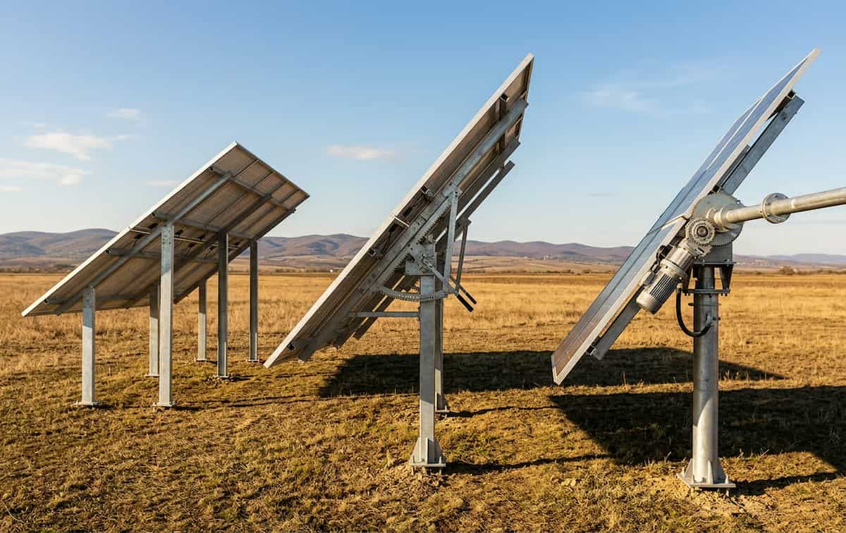 Structura de suport pentru montajul panourilor fotovoltaice la sol - trei panouri fotovoltaice industriale in camp deschis, munti pe fundal